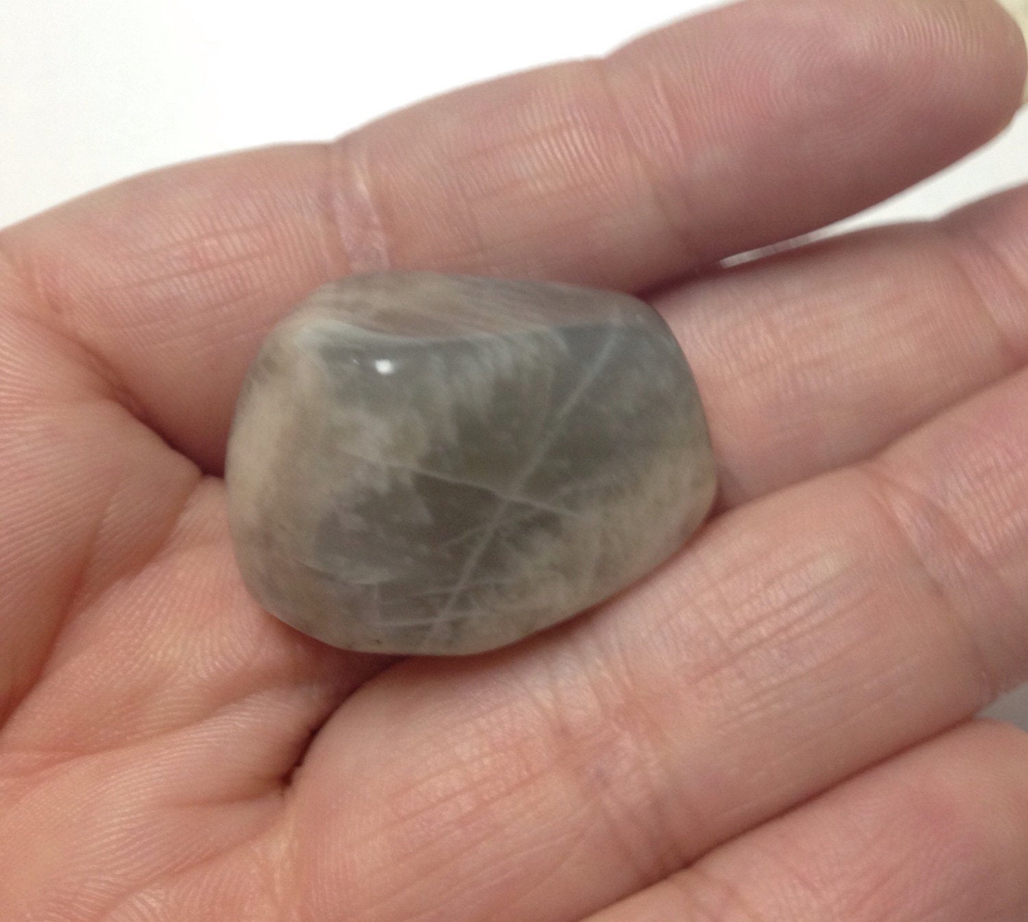 Black Moonstone gemstone in hand, travelers protection stone for Gemini zodiac, polished and smooth