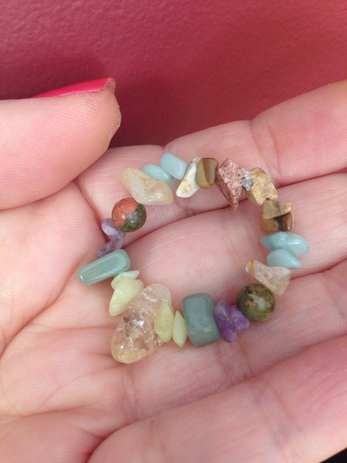 Hand holding colorful pocket stones including citrine, green aventurine, amazonite, amethyst, picture jasper, bowenite jade, and unakite