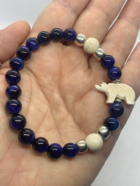 Polar bear bracelet with carved bone polar bear, blue tiger's eye and howlite beads on hand