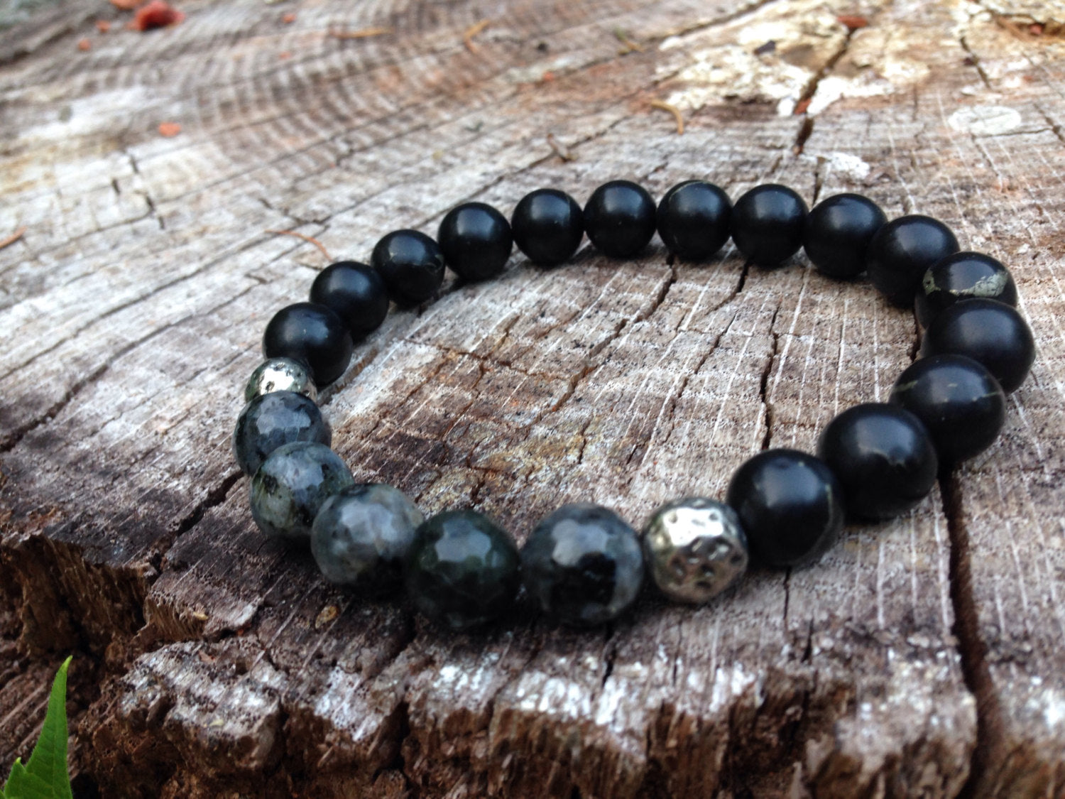 Mens bracelet made of black shungite and gray labradorite stones on wooden surface