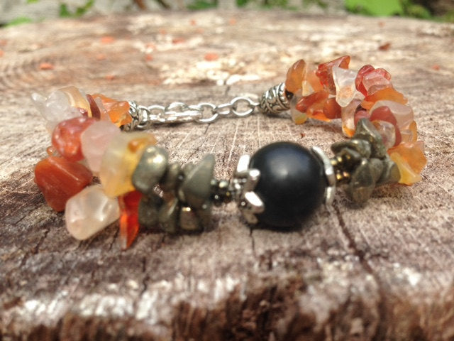 Ladies bracelet with Shungite, Carnelian, and Pyrite natural stones on rustic wood background