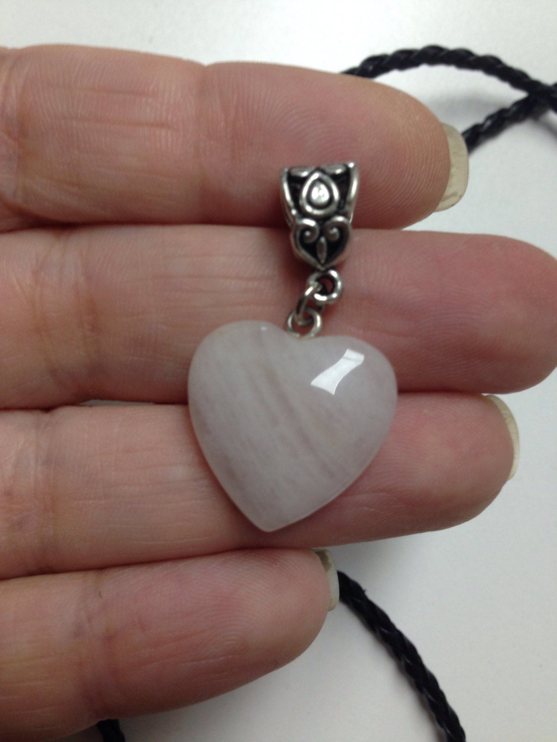 Heart pendant in rose Quartz held by hand with braided black cord
