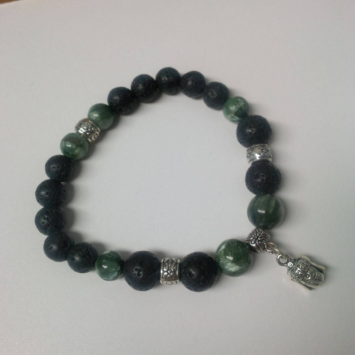 Lava and Seraphinite stone bracelet with Buddha charm and silver accents on white background