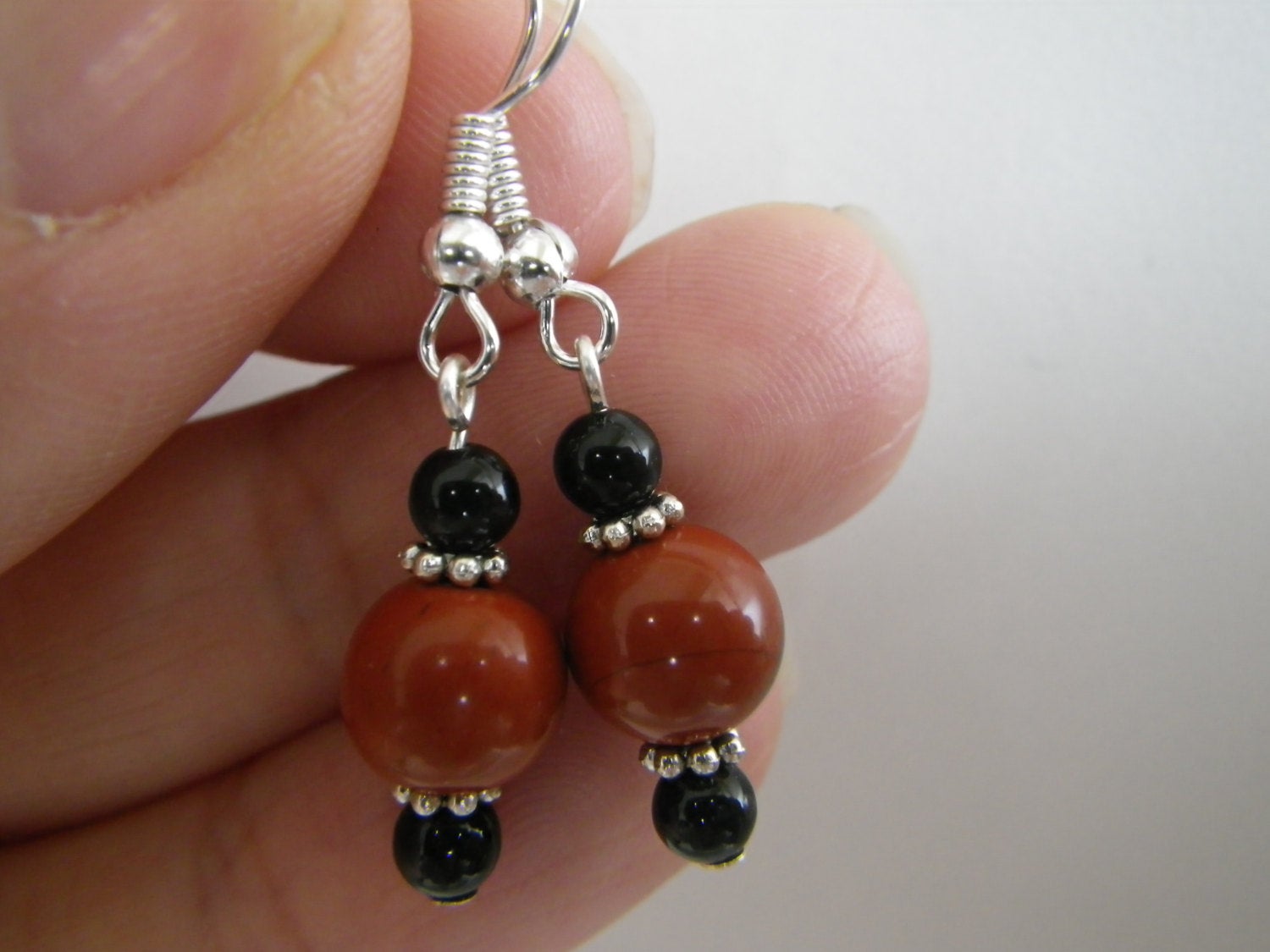 Women's earrings featuring red jasper and black onyx stones with silver tone findings, 1.5 inches long