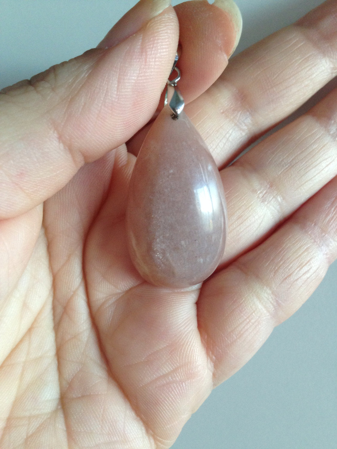 Chocolate colored teardrop moonstone pendant with 18K gold plated bail held in hand