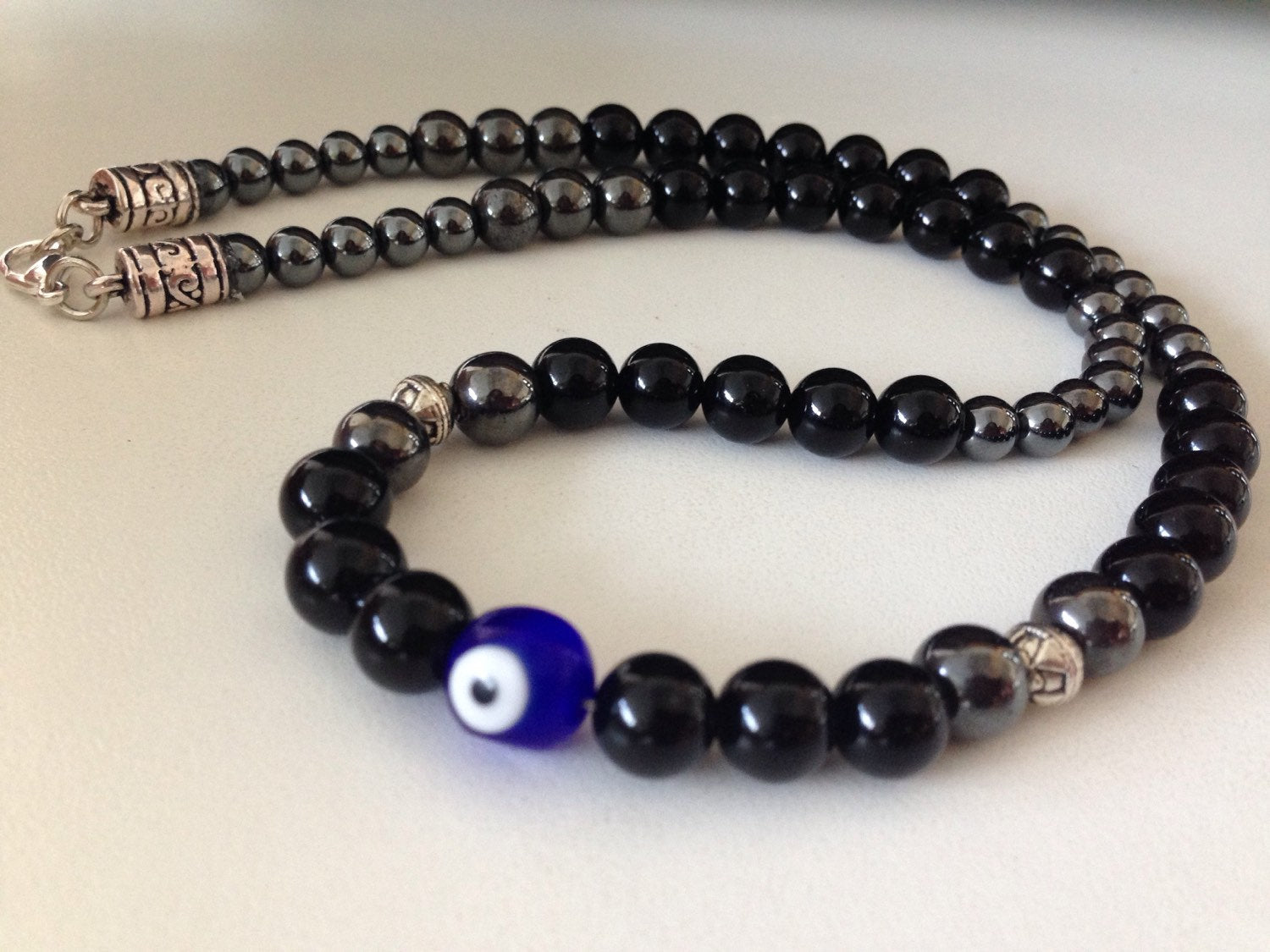 Men's necklace with black onyx, hematite beads, and a blue evil eye bead for protection