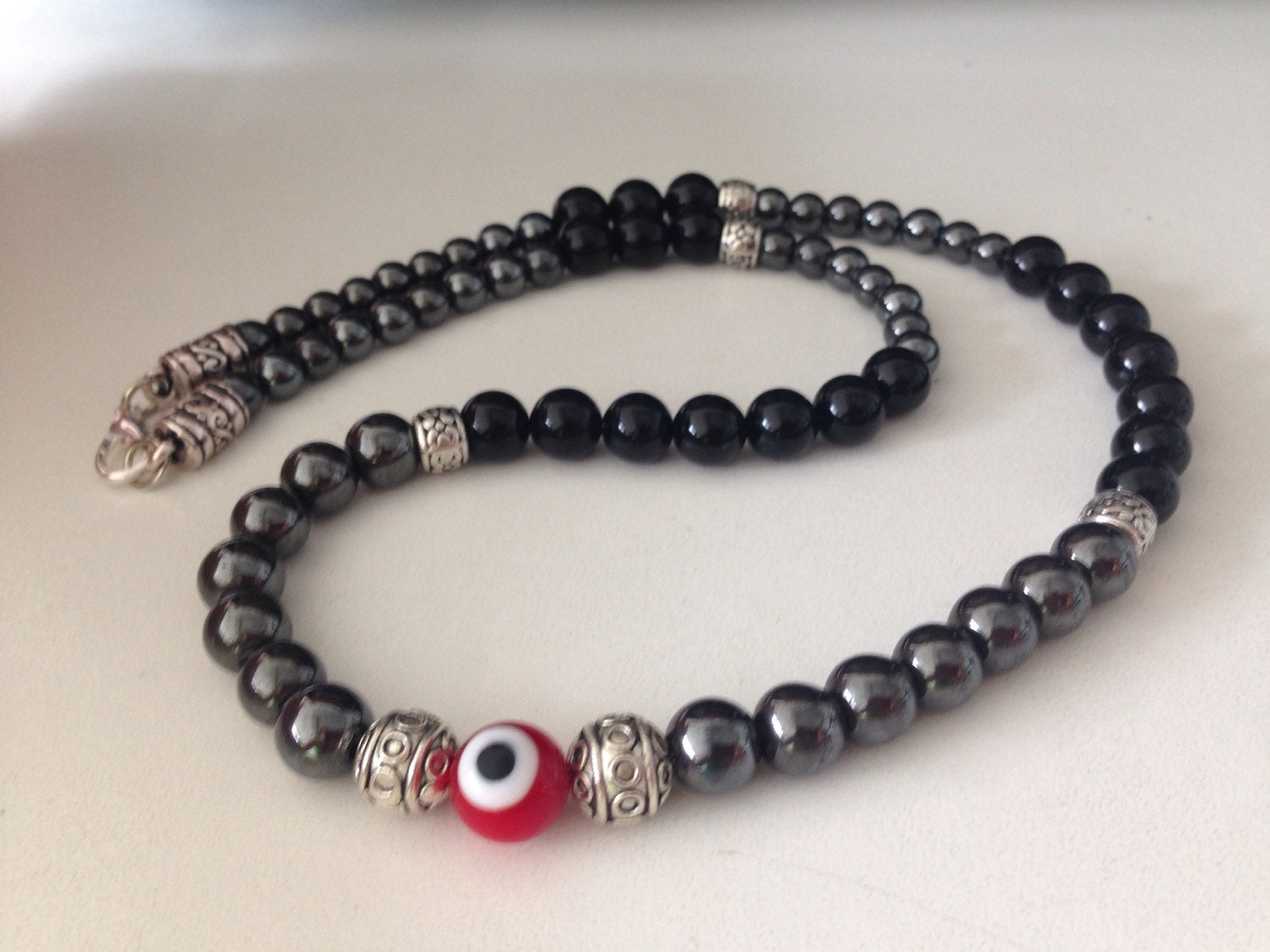 Men's necklace with black onyx, hematite beads, and red evil eye pendant with silver accents