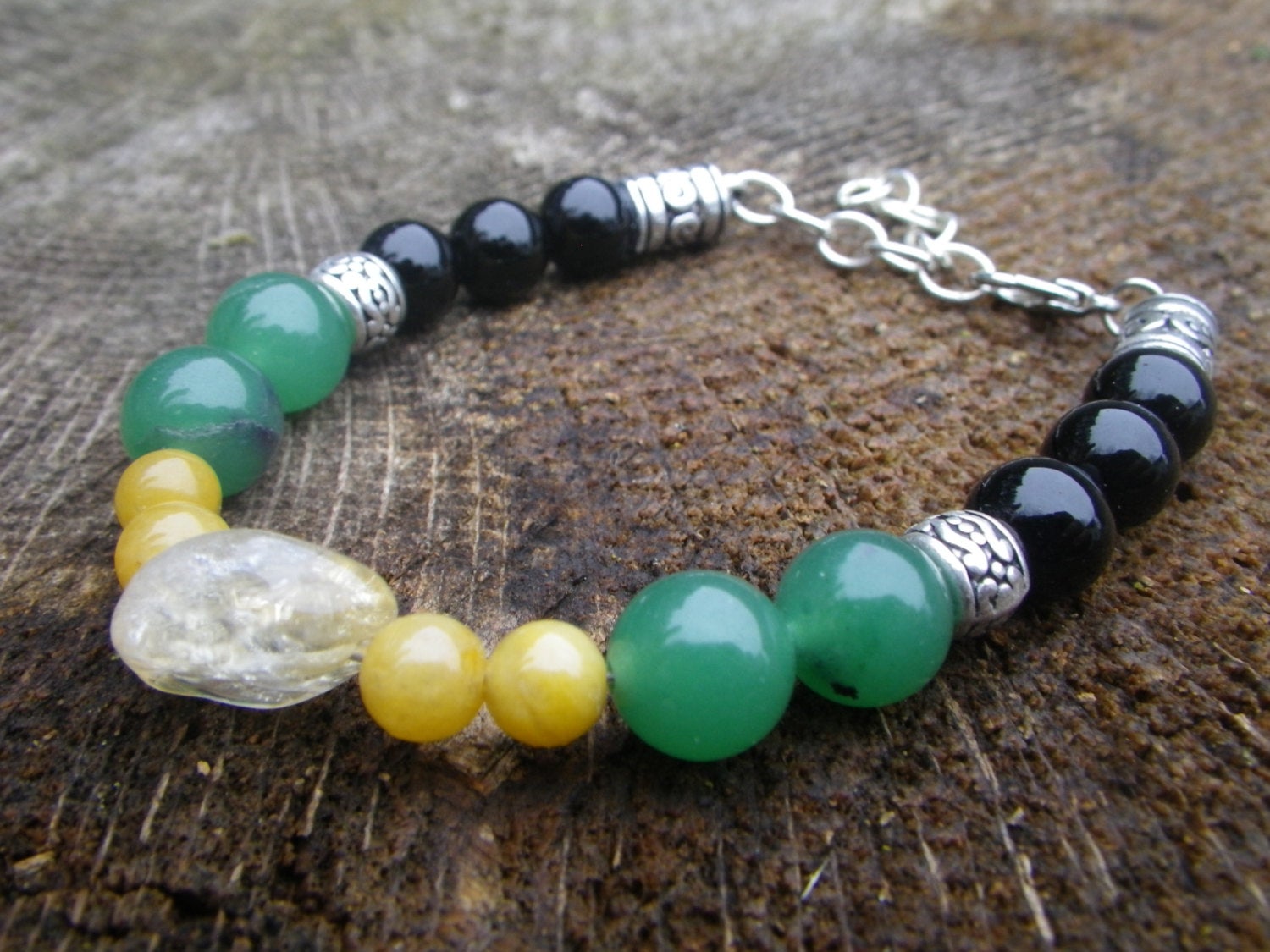 GOOD LUCK bracelet with yellow jade, green aventurine, citrine, and black onyx stones on wood background